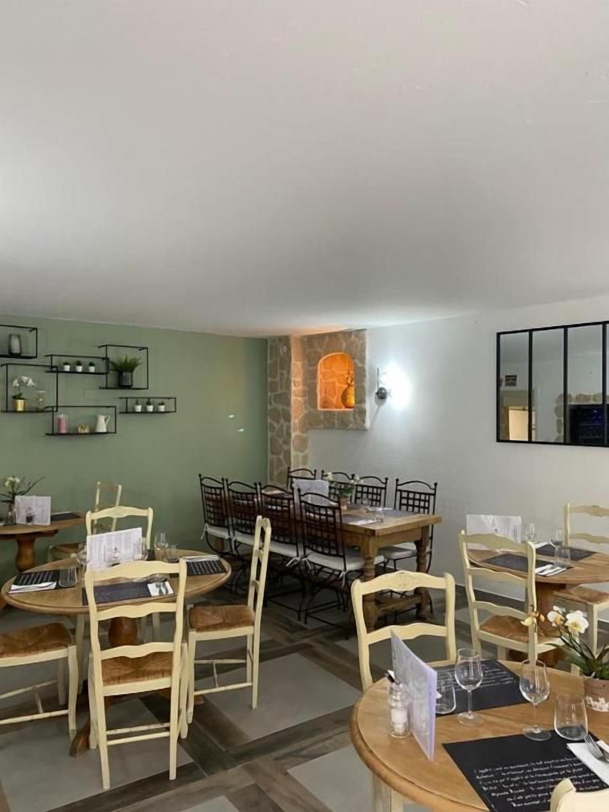 A dining area with wooden tables and chairs, a stone wall, and a mirror on the wall.