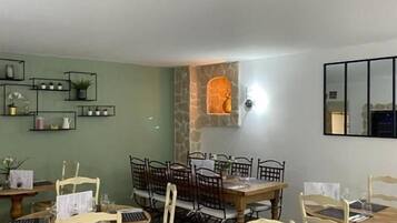 A dining area with wooden tables and chairs, a stone wall, and a mirror on the wall.