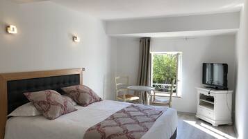 Une chambre d’hôtel avec un lit, une télévision, une petite table et une chaise.