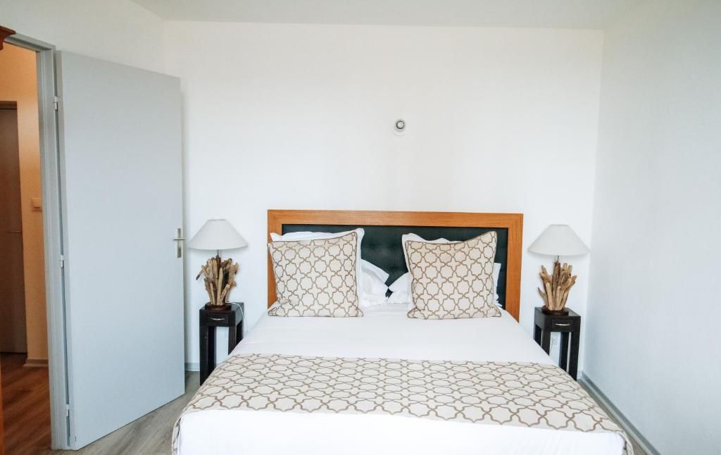 A hotel room with a bed, two bedside tables, and a door.