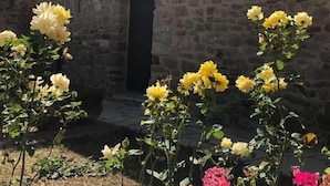 Un edificio de piedra con una torre de reloj, un cartel que dice “GALERIE D'ART” y un jardín con flores amarillas.