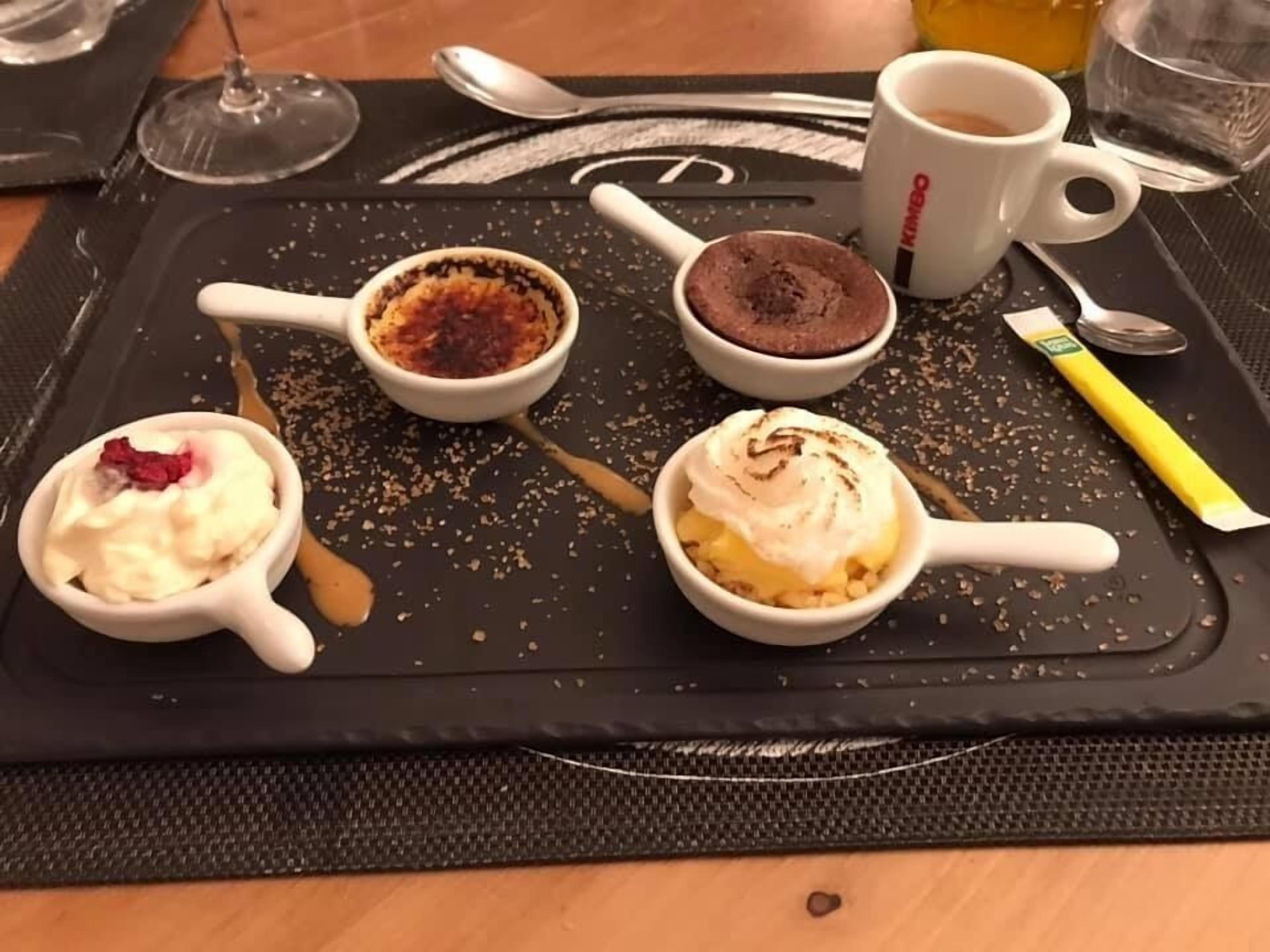 Un plateau contenant quatre ramequins à dessert, une cuillère, une tasse et un sachet de sucre, le tout posé sur un tapis noir.