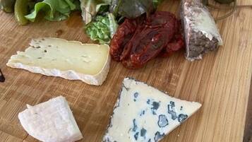 Une planche en bois garnie de différents fromages, de charcuteries et de cornichons.