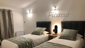Habitación de hotel con dos camas, una lámpara en la pared y una cortina.