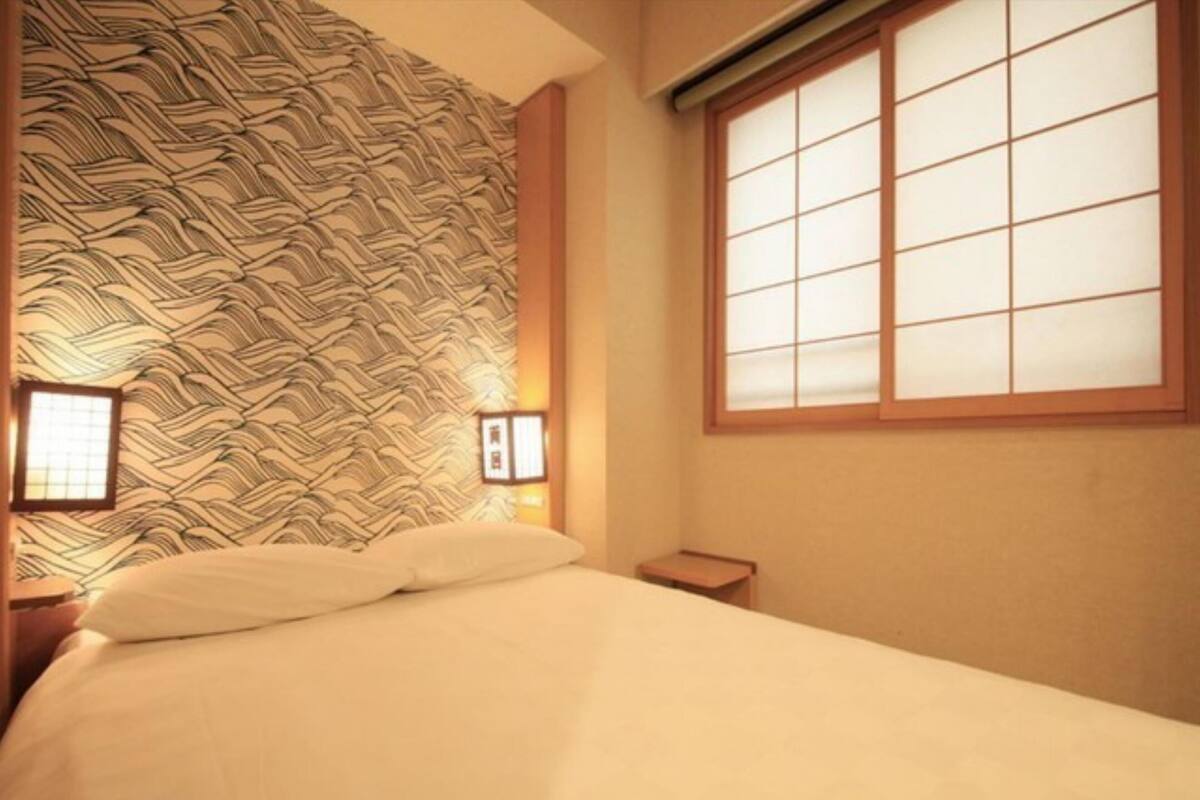 A room with a bed, a window with a grid pattern, and a wall with a wavy pattern.