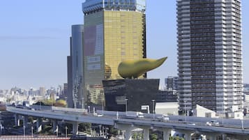 Un paisaje urbano moderno con rascacielos, una estructura amarilla distintiva y un puente sobre un río.