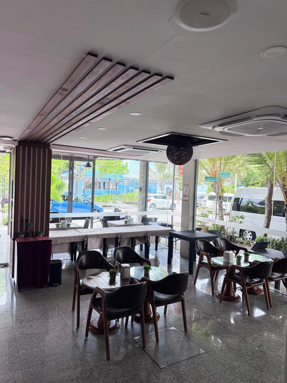 Un espace de restauration intérieur avec des tables et des chaises, de grandes fenêtres et une vue sur la rue.