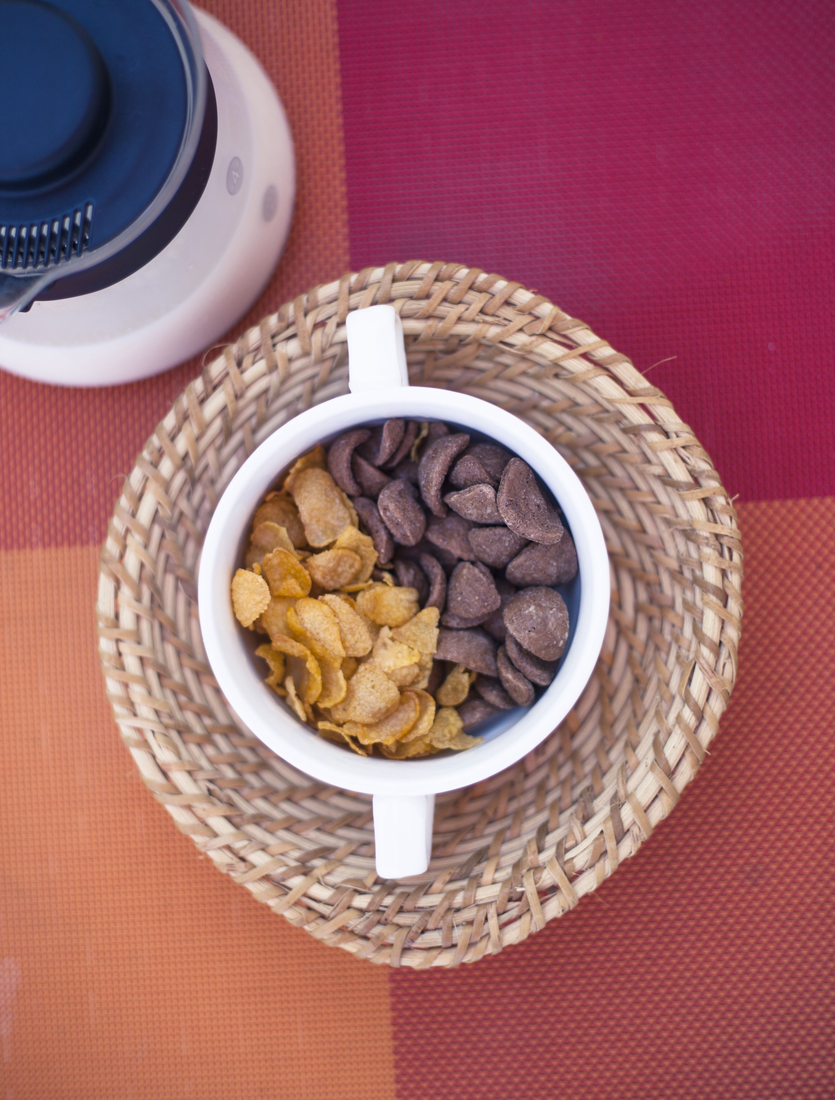 A bowl of snacks on a woven mat.