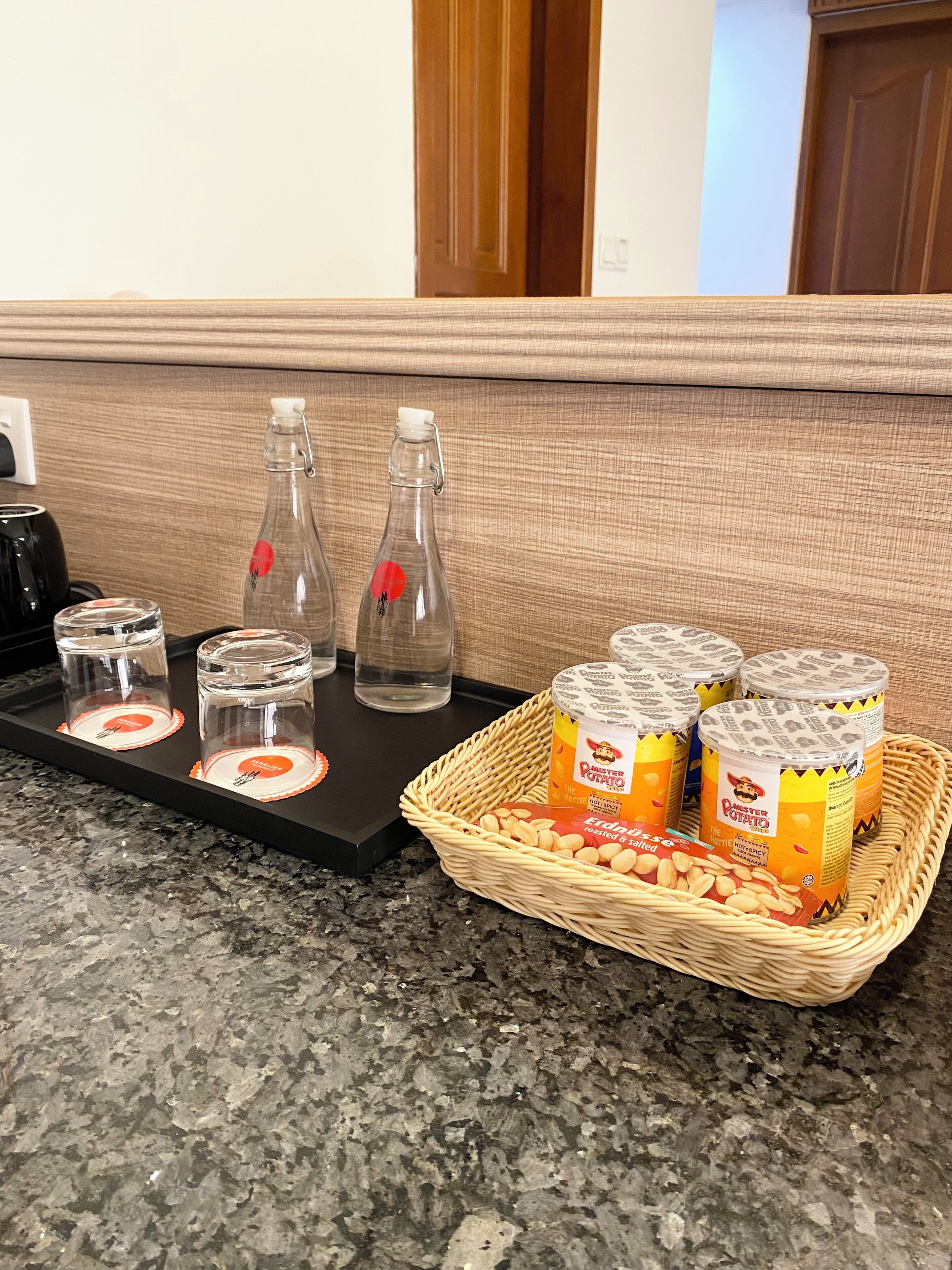 A kitchen counter with a tray holding jars of mustard and a basket of roasted potatoes.