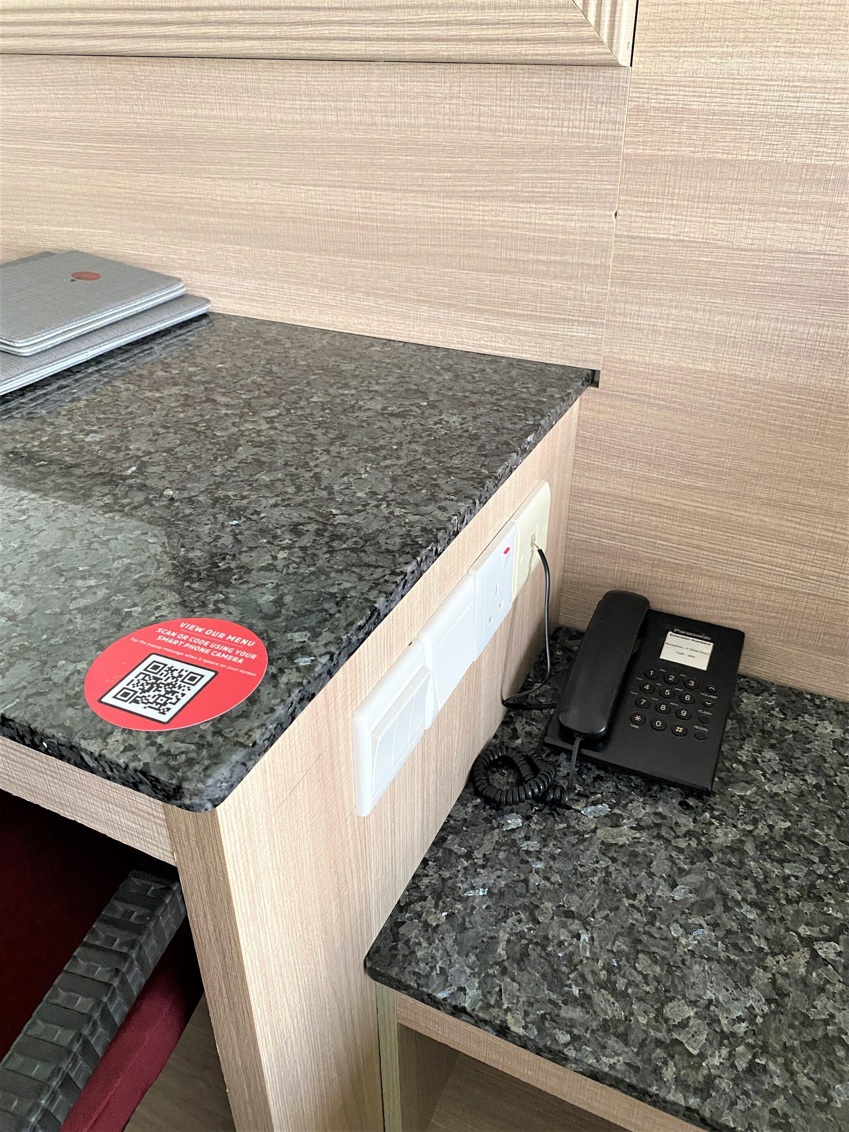 En receptionsdisk med bordplade i granit, en telefon og en QR-kode klistermærke.