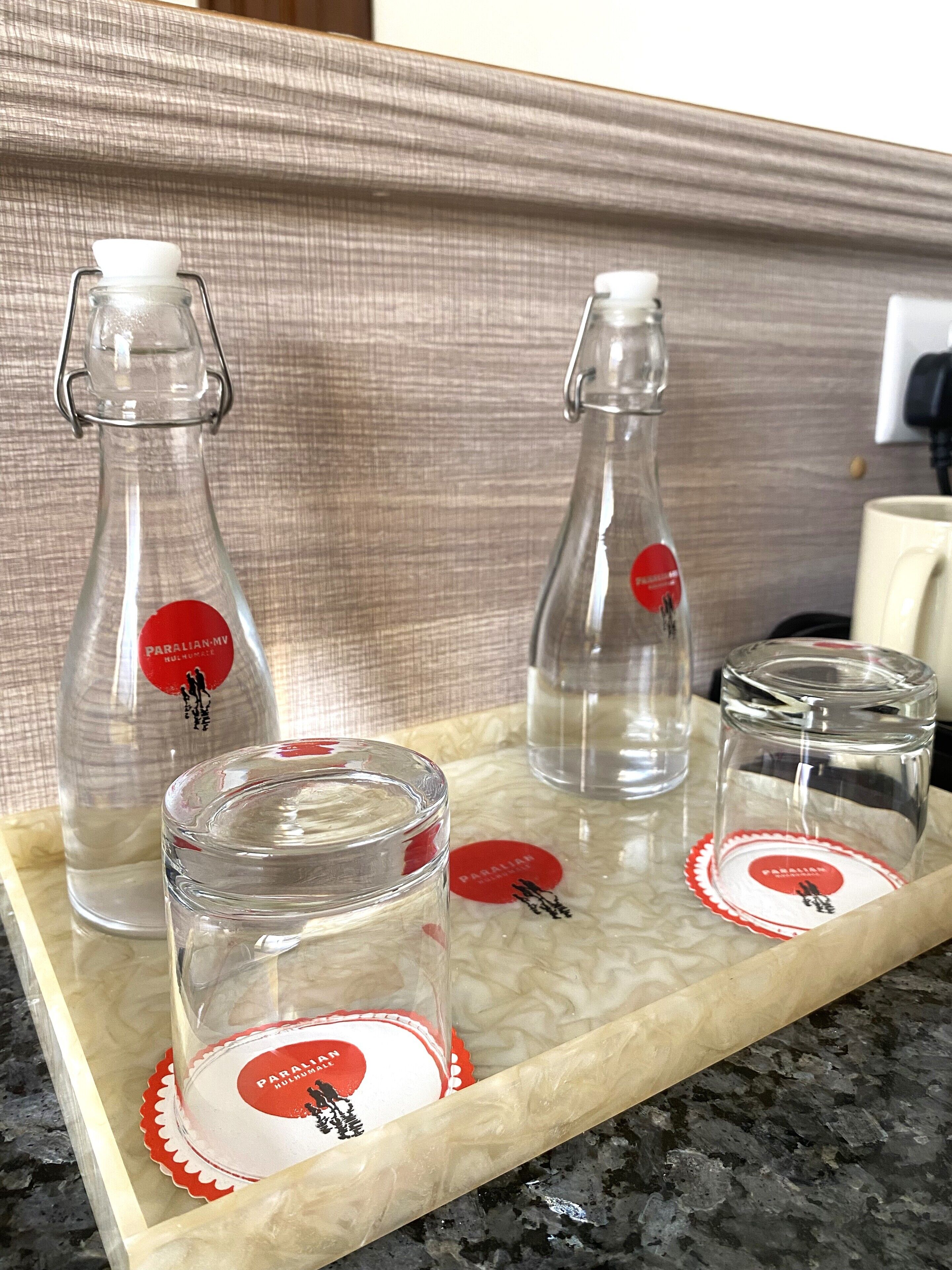 Una bandeja con tres botellas de vidrio y dos frascos de vidrio, cada uno con una etiqueta roja.