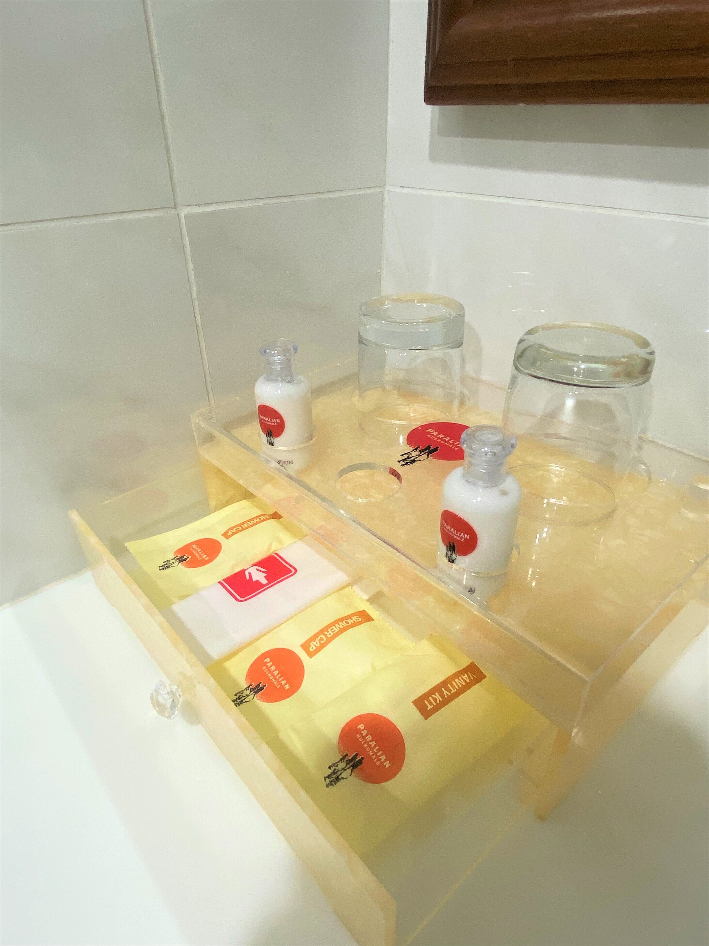 Un baño con repisa de vidrio para artículos de aseo y un perchero para toallas.