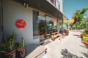 Un café con terraza, plantas en macetas y cielo despejado.