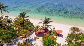 A beach view with a small hut and outdoor seating area.