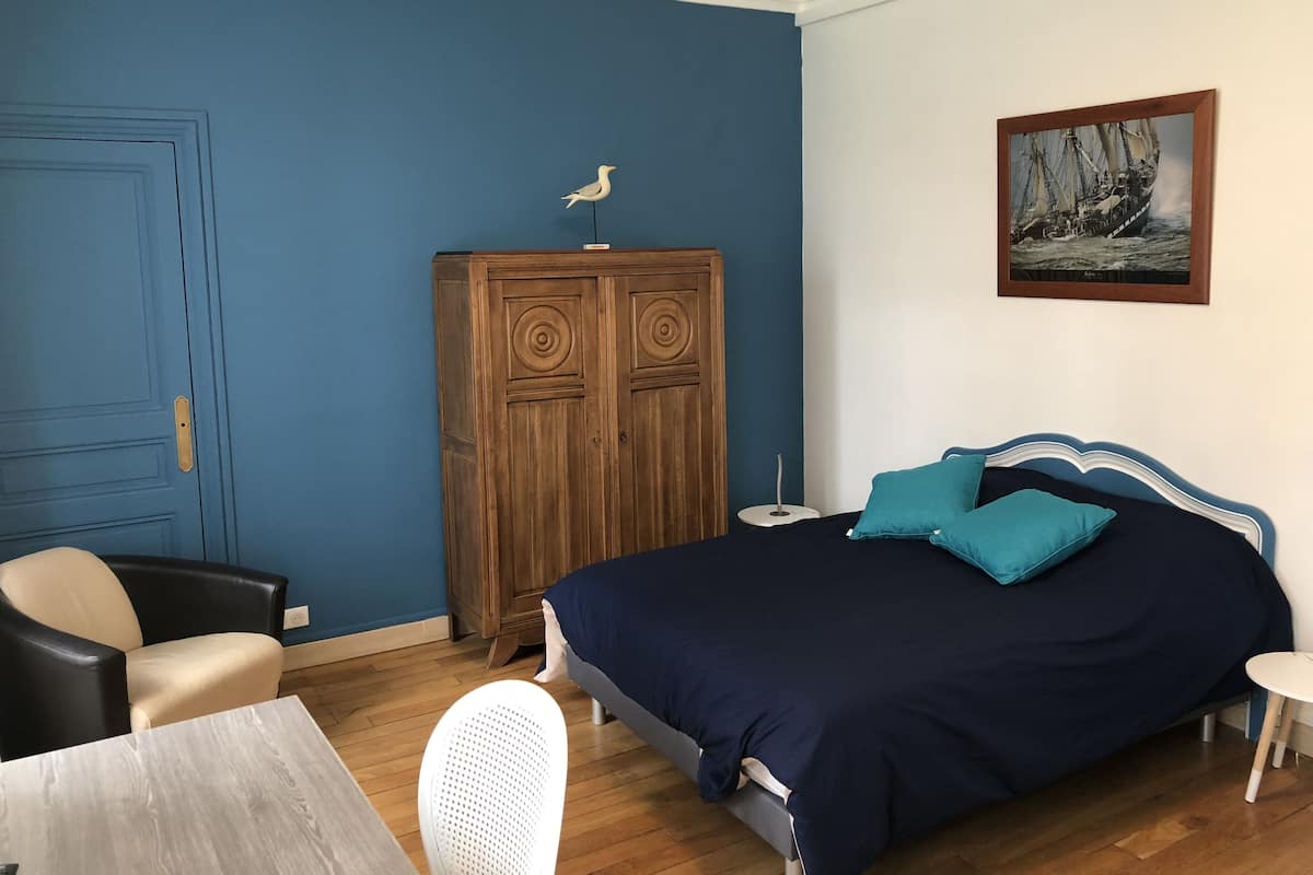 Une chambre  à coucher avec un lit, une armoire en bois, un bureau et une chaise.