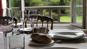 Una mesa de comedor dispuesta con copas de vino, platos y una hogaza de pan.