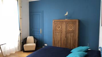 Un dormitorio con una cama grande, un armario de madera, una silla y un ventanal con cortinas.