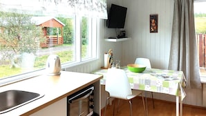 A kitchen with a wooden countertop, a sink, a stove, and a dining area with a table and chairs. - Ásgeirsstaðir Cottages (Eidar)