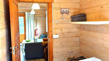 Una habitación de cabaña de madera con una cama, una lámpara colgante, una mesita con una silla y una bicicleta como adorno en la pared.