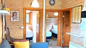 A cozy cabin interior with a wooden ceiling, a blue sofa, a dining table, and a kitchen area. - Ásgeirsstaðir Cottages (Eidar)