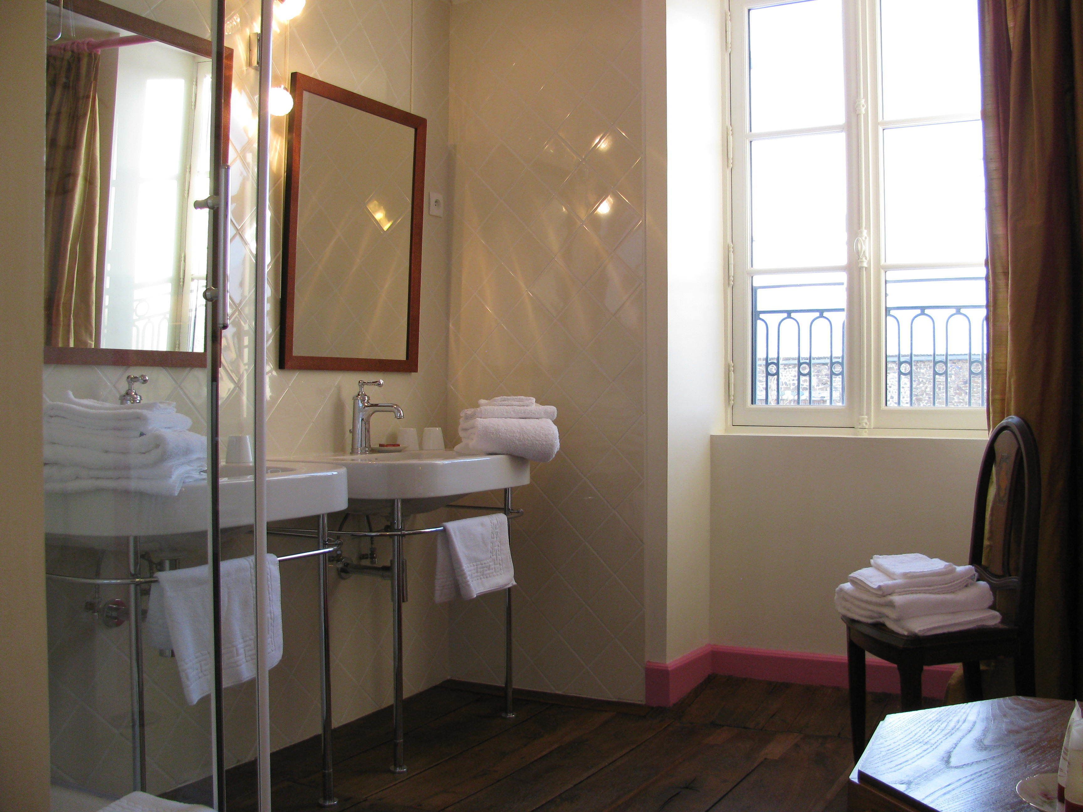 A bathroom with a glass shower enclosure, a sink with a mirror, and a window with a view of a balcony.