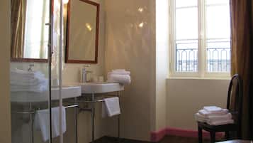 A bathroom with a glass shower enclosure, a sink with a mirror, and a window with a view of a balcony.