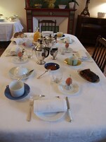 Une table à manger dressée avec des couverts, des assiettes, des tasses et une variété de plats.