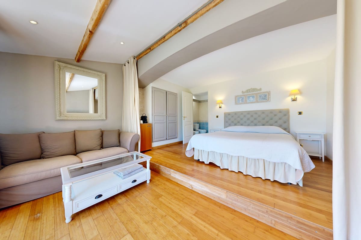 A bedroom with a bed, a sofa, a mirror, and a wardrobe.