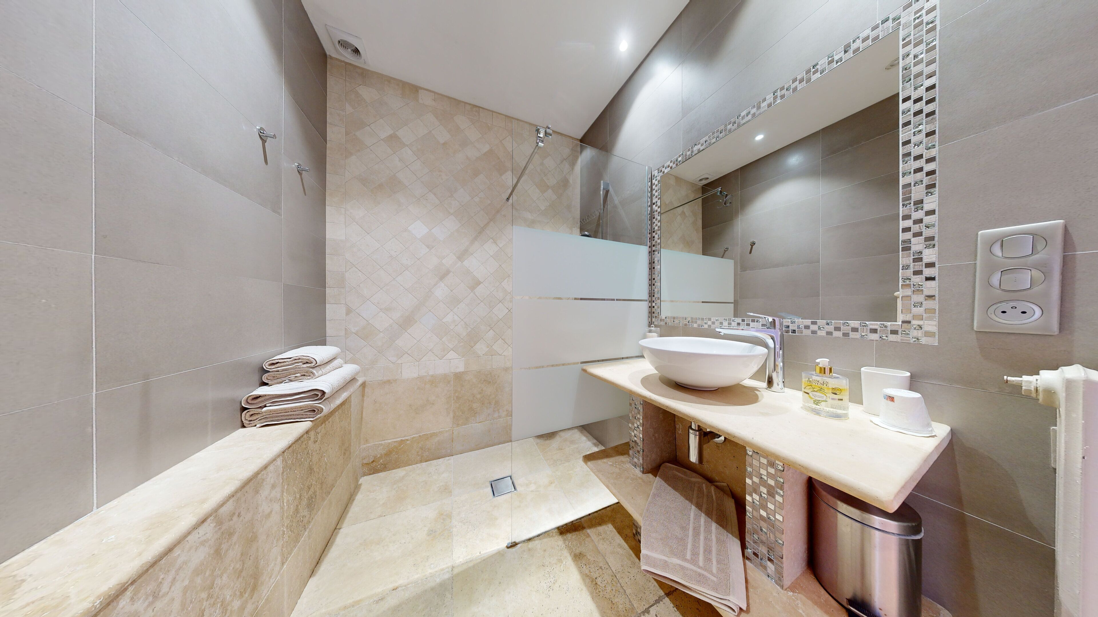 Un baño moderno con un espejo grande, un lavabo blanco y una zona de ducha.