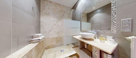 Une salle de bain moderne avec un grand miroir, un lavabo blanc et un espace douche.