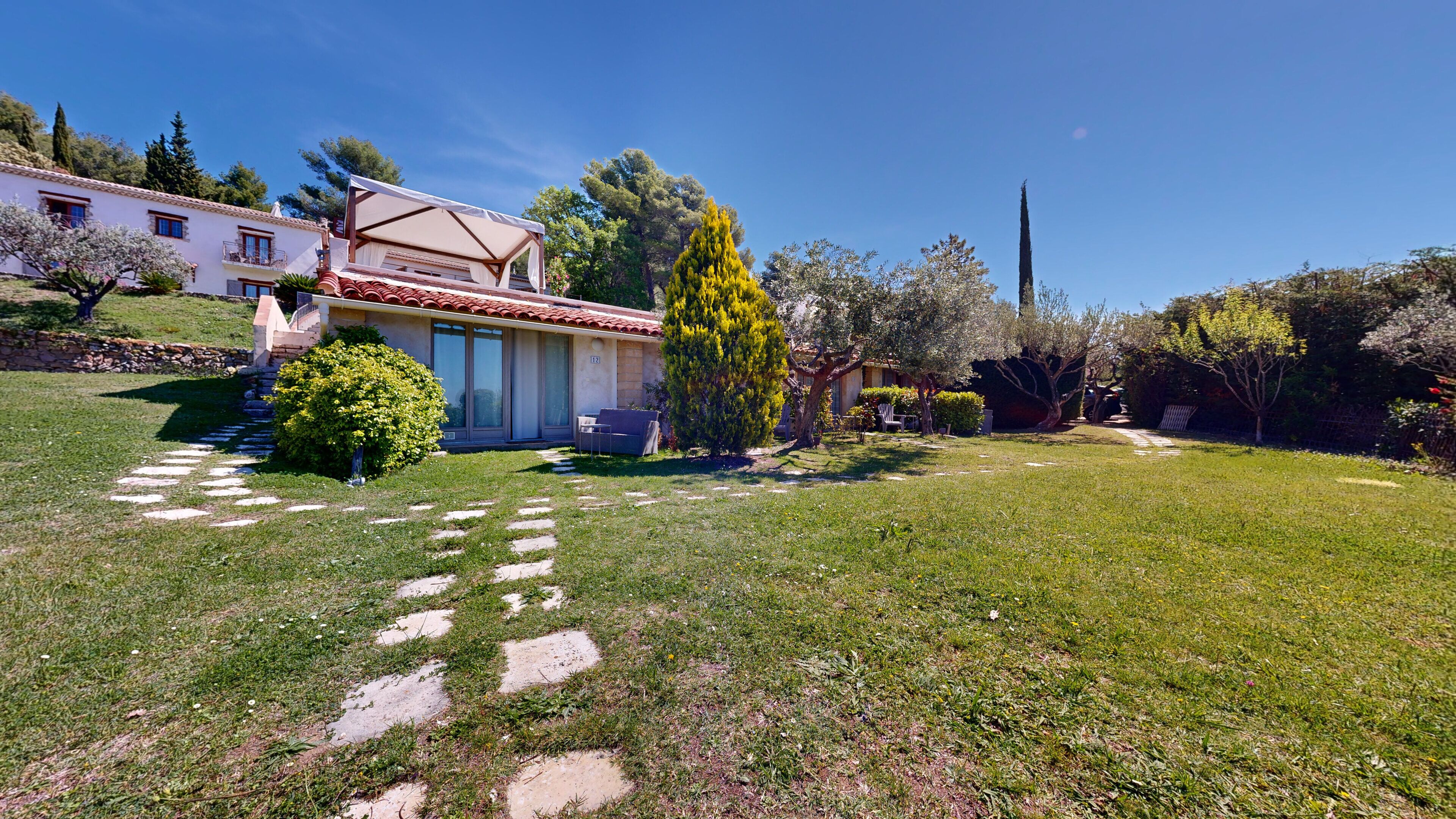 A house with a red-tiled roof, a covered patio, and a stone pathway leading to the entrance.