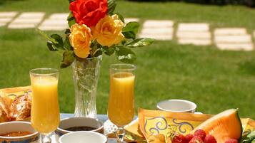A breakfast setup with a table, a vase of flowers, and a basket of fruit.