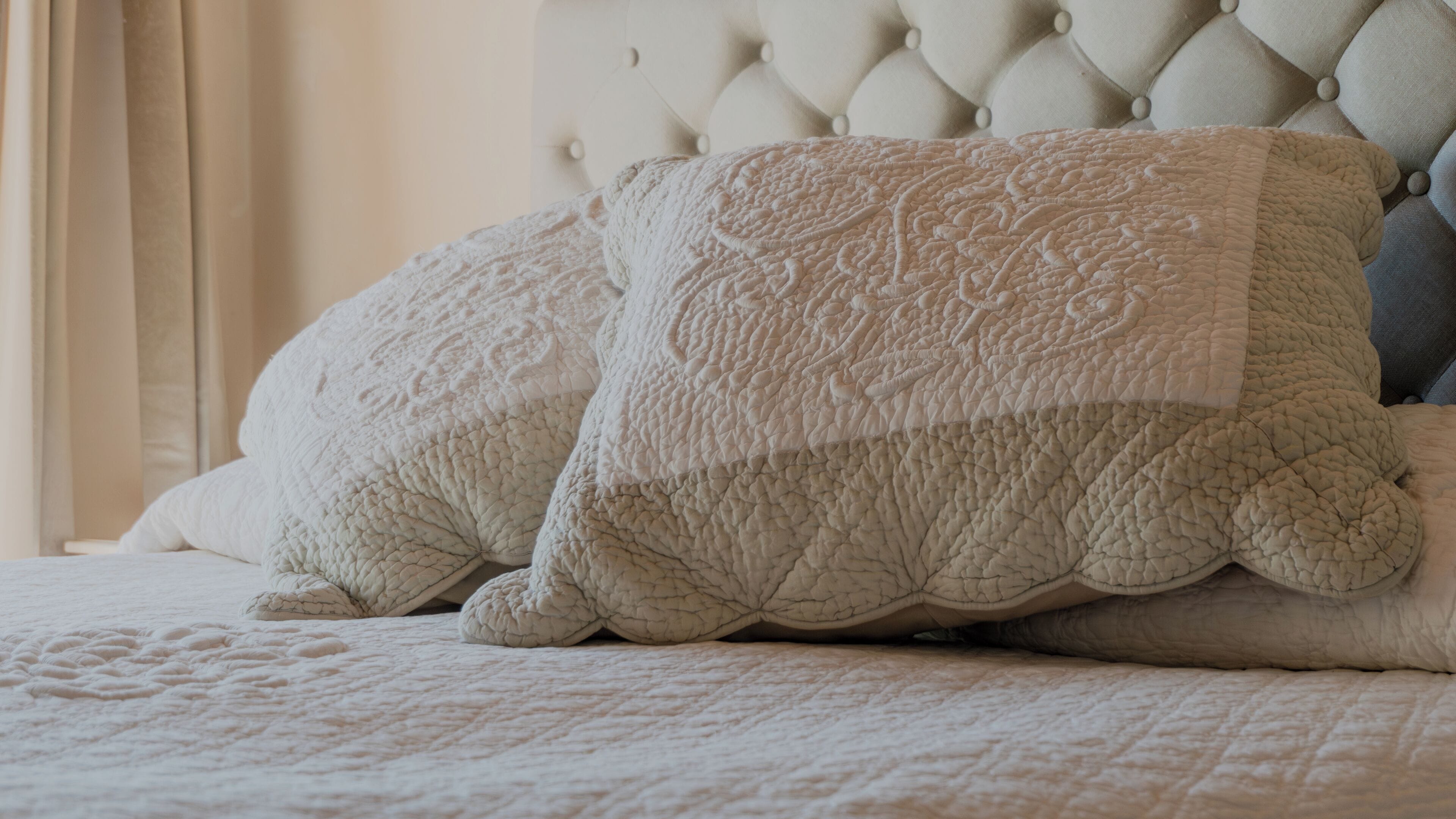 A bed with a tufted headboard and decorative pillows.