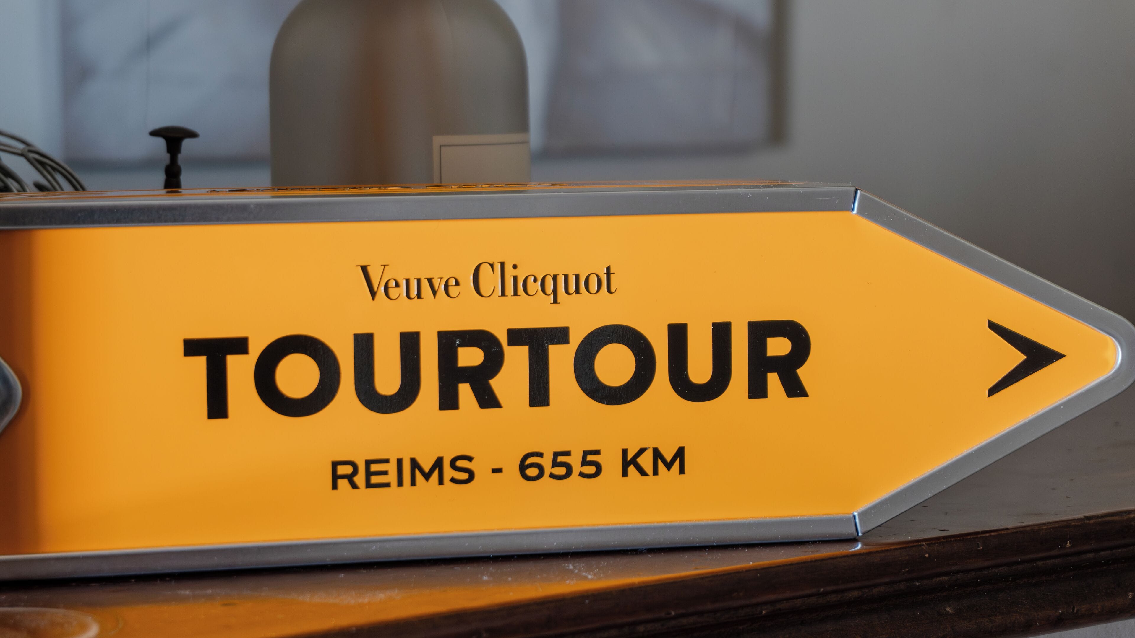 A sign indicating a tour route with the text "TOURTOUR" and "REIMS - 655 KM".