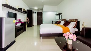 A modern hotel room with a bed, a sofa, a dining table, and a TV. - The Dlife (Hat Yai)