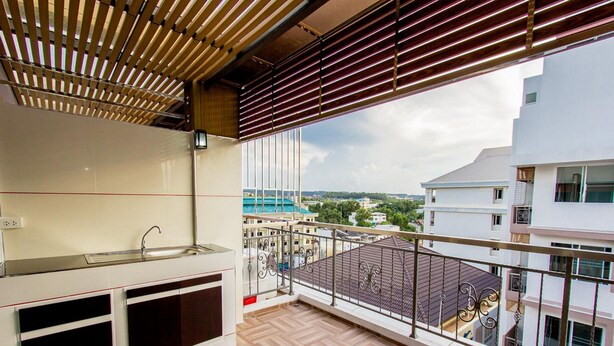 A balcony with a herringbone floor, a sink, and a view of buildings and greenery. - The Dlife (Hat Yai)