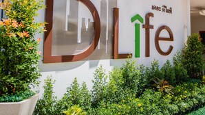 A sign with the text "DLife" and an upward arrow, surrounded by greenery. - The Dlife (Hat Yai)