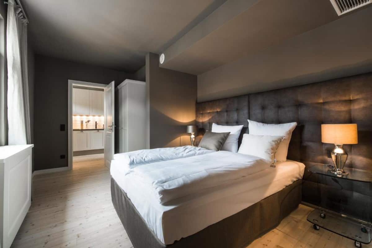Ein modernes Schlafzimmer mit einem großen Bett, Nachttischlampen und einem dunklen Kopfteil.