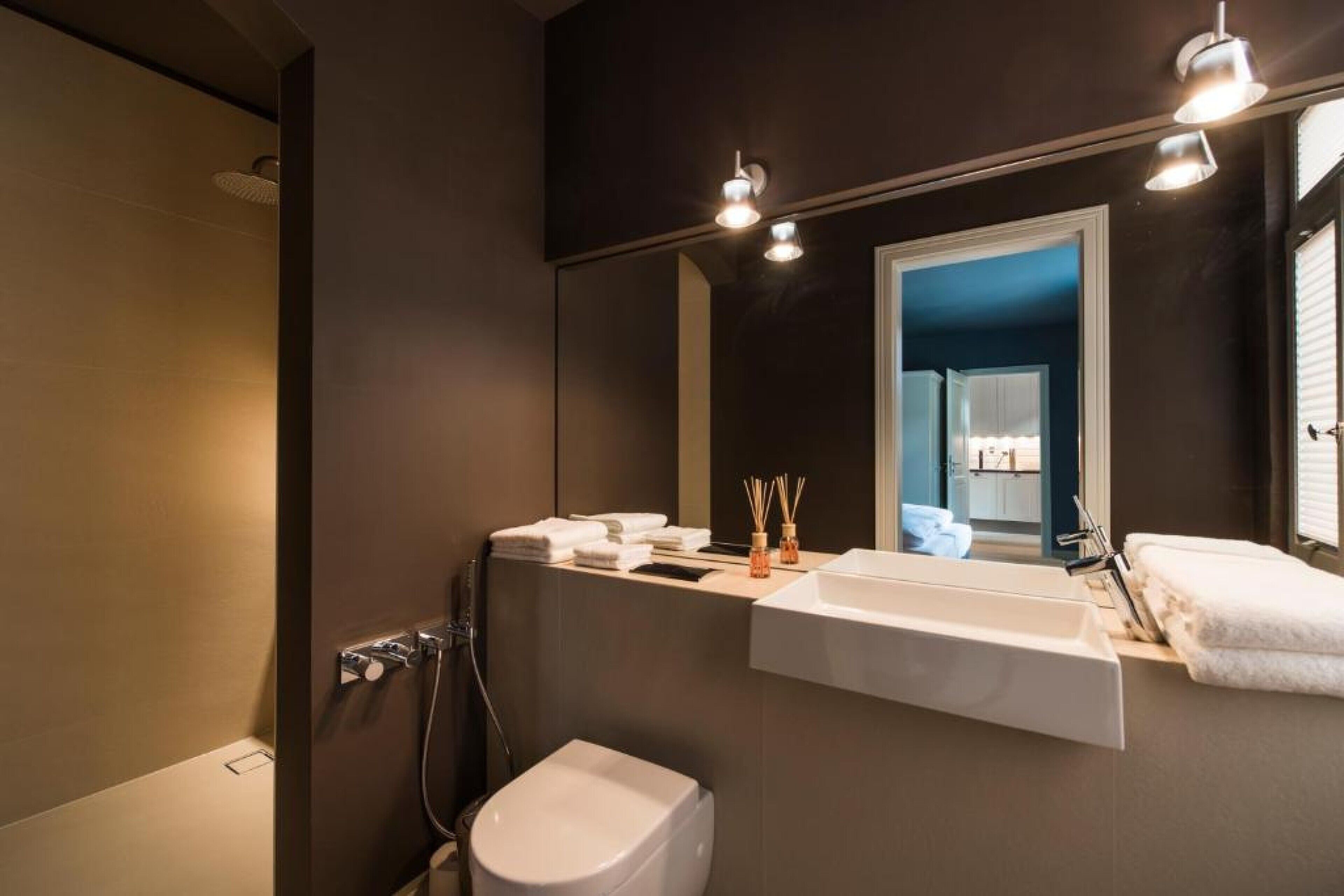 Een moderne badkamer met een grote spiegel, een witte wastafel en een toilet.