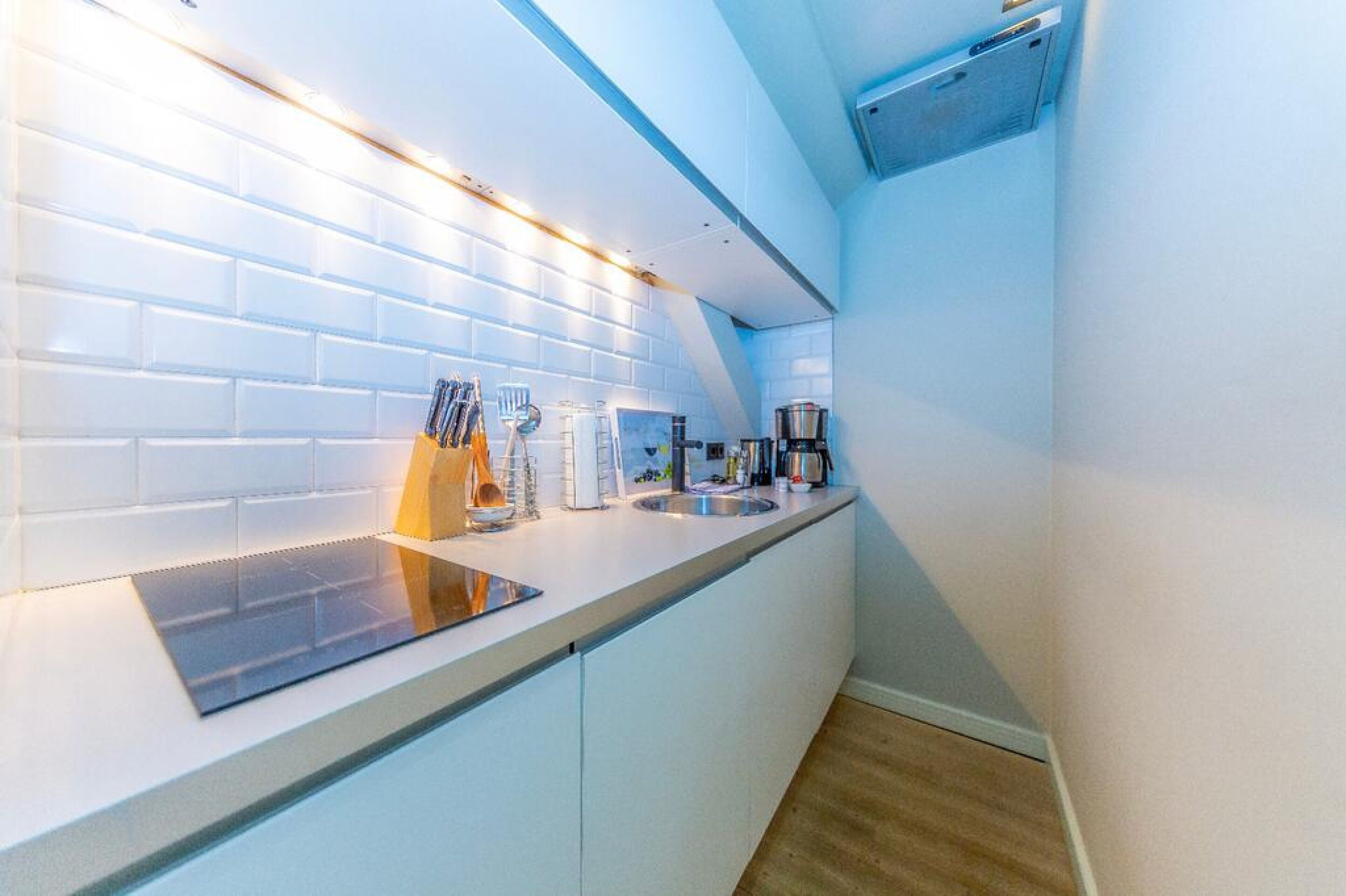 Une cuisine moderne avec des meubles blancs, une plaque de cuisson à induction noire et des appareils électroménagers en acier inoxydable.