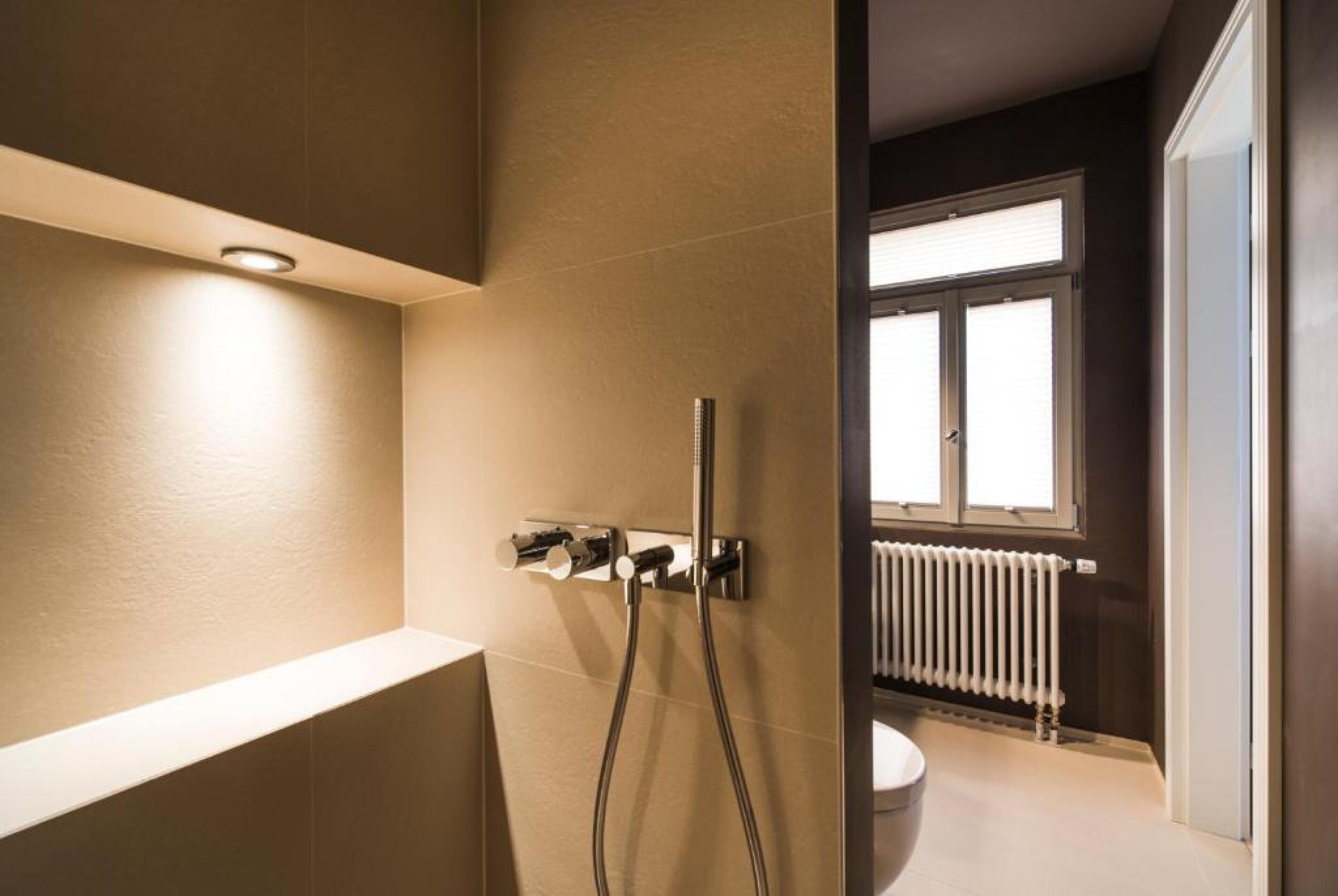 A modern bathroom with a shower, a toilet, and a window.