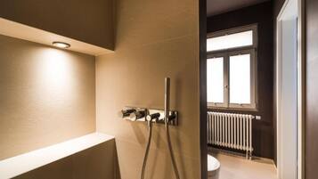 A modern bathroom with a shower, a toilet, and a window.