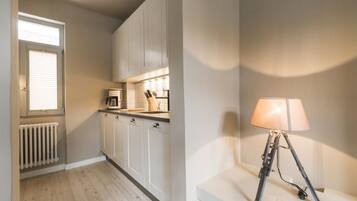 A modern kitchen with white cabinets, a coffee machine, and a lamp on a white stand.