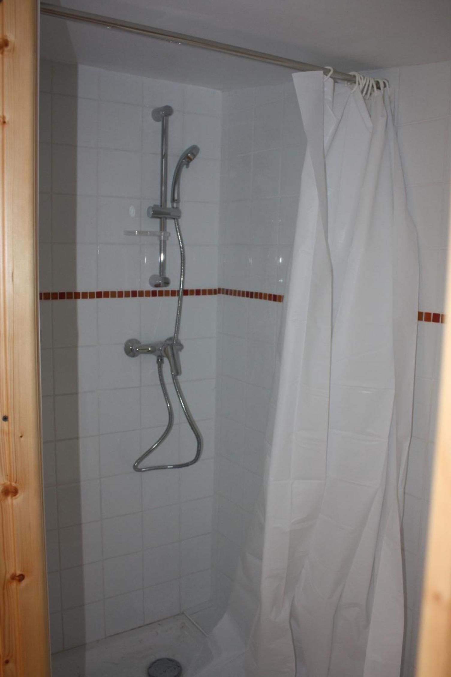 Ein Duschbereich mit Duschkopf, Handbrause und einer Duschvorhang.