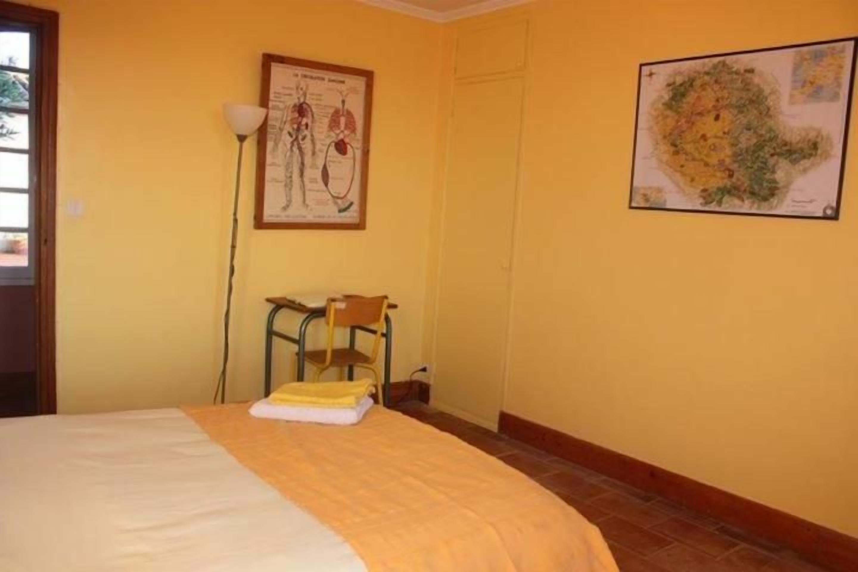 Um quarto com uma cama, uma cadeira, um mapa na parede e um abajur.
