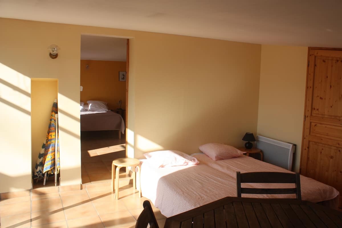 Une chambre à coucher avec un lit, une chaise, une petite table et une porte en bois.