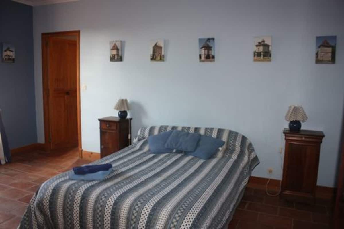 Une chambre à coucher avec un lit, une porte en bois, une table de chevet et une lampe.
