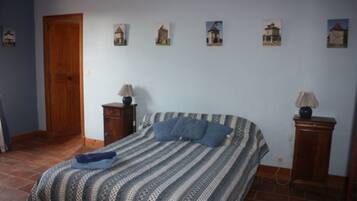 Um quarto com uma cama, porta de madeira, mesa de cabeceira e abajur.