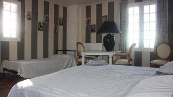 A hotel room with two single beds, a small table with a lamp, and a chair.