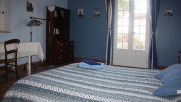 A bedroom with a bed, a dresser, a chair, and a window with curtains.